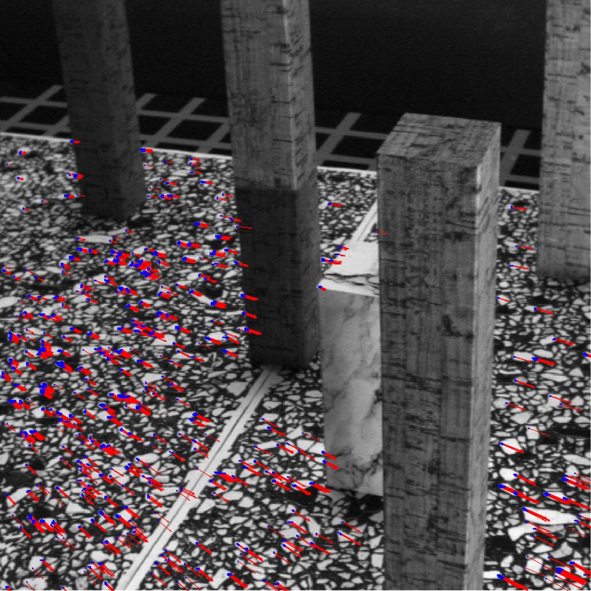 Flow vectors surviving the confidence threshold, with RANSAC inliers marked in blue. Only the textured gravel produces reliable flow — the smooth concrete columns are aperture-problem territory and drop out entirely, which is the correct behaviour rather than a failure.